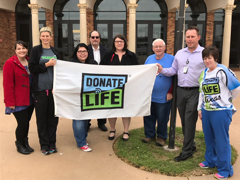 group holding up Donate For Life flag in front of coliseum