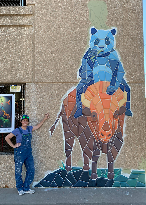 Jesse Baggett stands beside the mural before the painting was finished for the background on the mural.