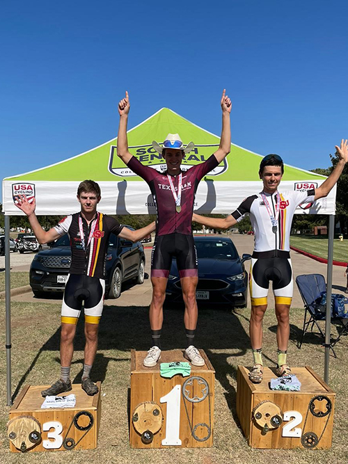 winners from cycling race rise up on their bikes to receive medals