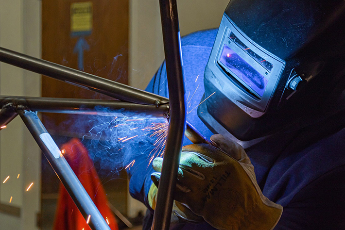 FSAE team member works on a part with safety mask on