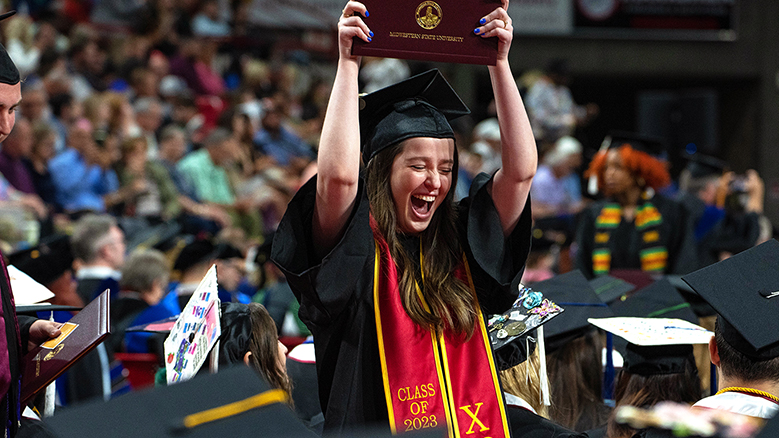 Graduate celebrates with cap raised above her head at MSU Texas graduation