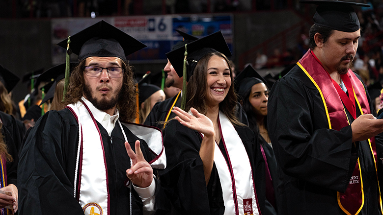 Graduates show their joy and one waves to crowd