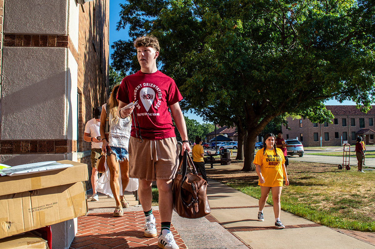 Mustangs Move-In group walks carrying bags up the sidewalk