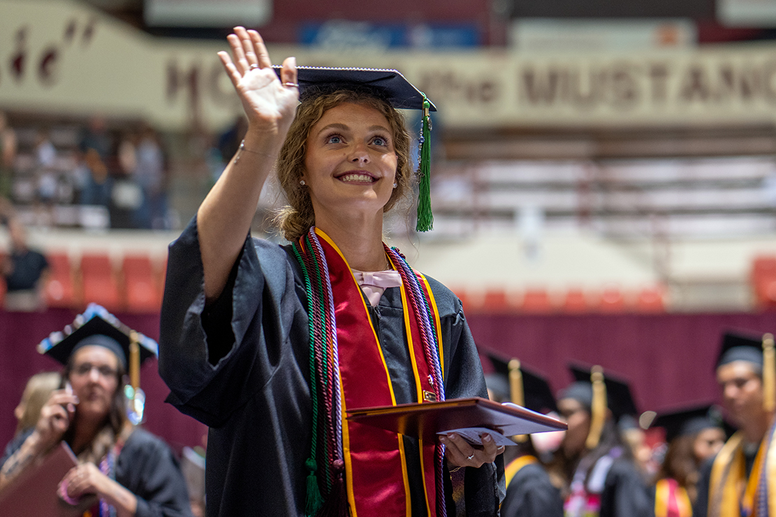 Graduate at commencement waves to the crowd