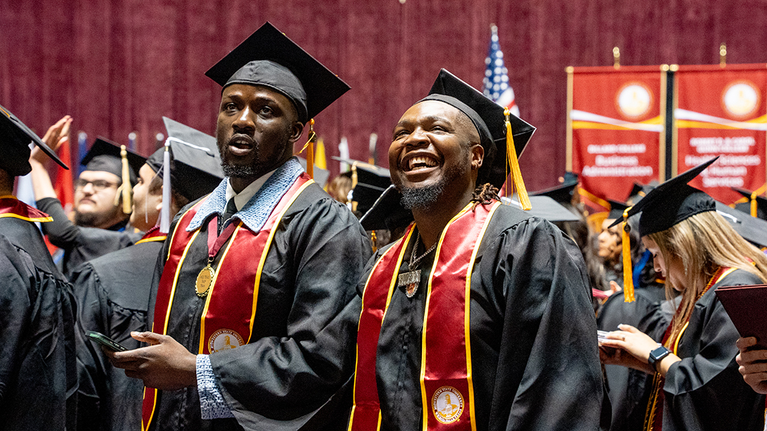 Samuel Olatunde with a fellow graduate at D.L. Ligon Coliseum in December 2024