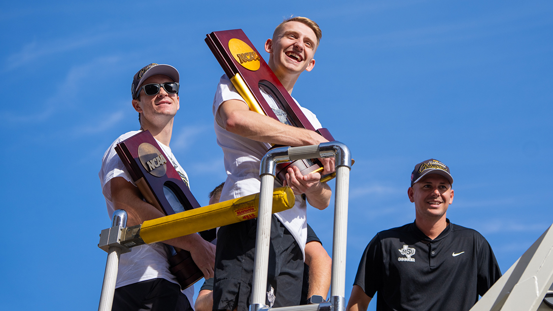 Soccer team members hold up the trophy