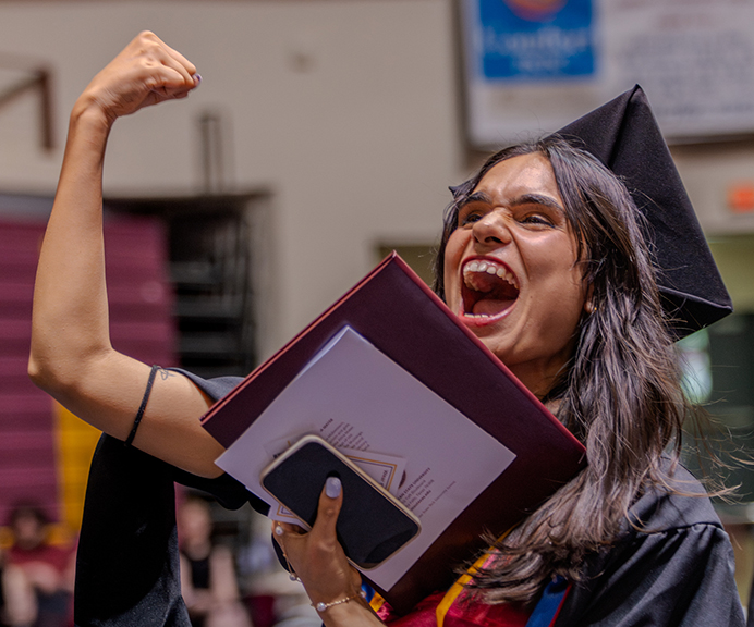 Graduate pumps her fist in celebration of the achievement