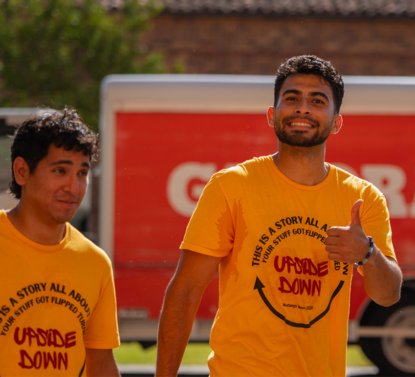 Two young men in gold shirts help on Move-In Day