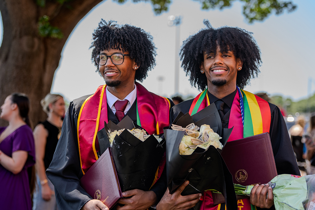 Two graduates smile outside of D.L Ligon on May 16